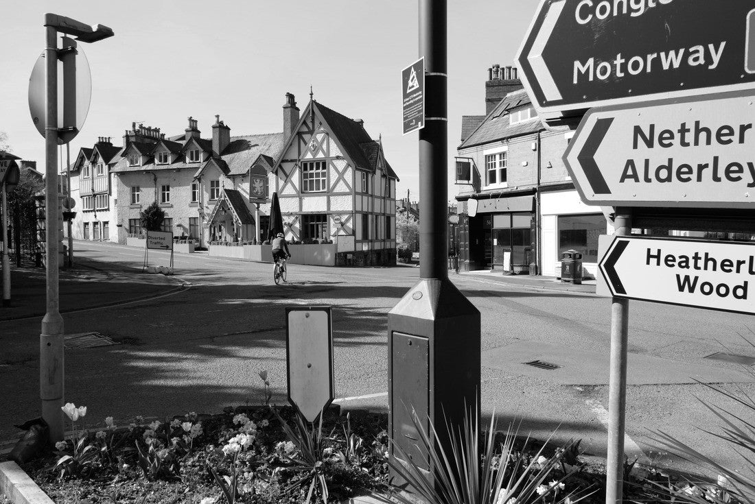 Alderley Edge (town), Cheshire, England, United Kingdom, street signs, shops and public house near the town center, with street border flowers and a cyclist 2000pc PuzzleBlack and White