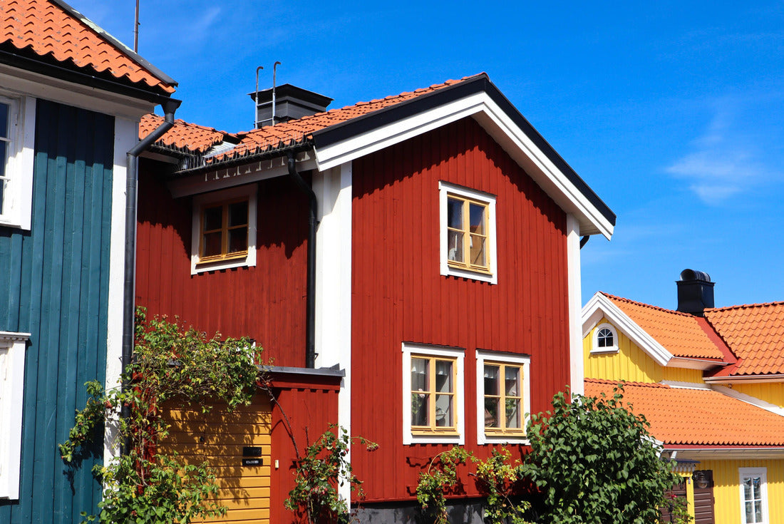 The facade of a red Swedish house with a blue house on the left and yellow houses on the right with orange tiled roofs in Västervik, Sweden 2000pc Puzzle