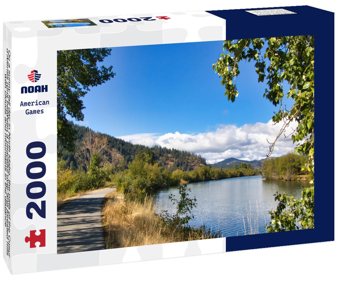 On a sunny fall day in North Idaho, the path of the Coeur d'Alenes runs between a peaceful river and forested hills, with clouds and mountains in the distance 2000pc Puzzle