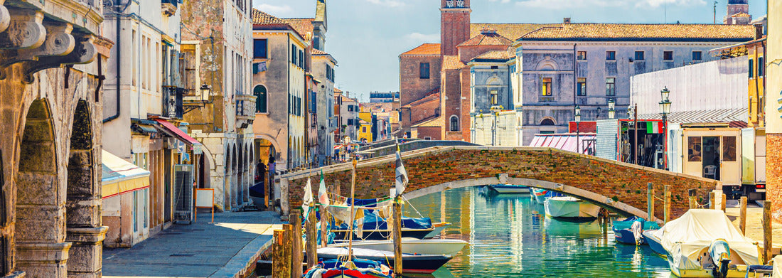 Noah Jigsaw Puzzle Chioggia cityscape with narrow water canal with colorful boats, old buildings, brick bridge and tower of the church San Giacomo Apostolo, blue sky in summer, Veneto region, northern Italy panorama 1000 pieces