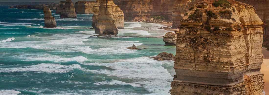 Noah Jigsaw Puzzle Blue green ocean and beach with sandbanks cliffs and waves with close view of The twelve apostles and cliffs in the shadow of the sunset in Victoria, Australia against a orange cloudy sky panorama 1000 pieces
