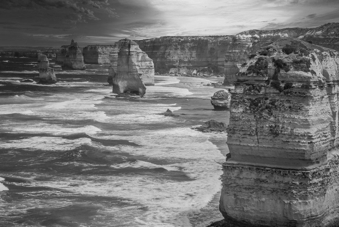 Noah Jigsaw Puzzle Blue green ocean and beach with sandbanks cliffs and waves with close view of The twelve apostles and cliffs in the shadow of the sunset in Victoria, Australia against a orange cloudy sky in black white 2000 pieces
