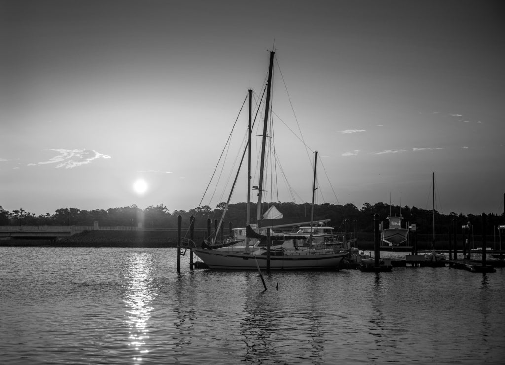 Sailboats at Sunrise at the marina on calm water in Beaufort North Carolina in black white