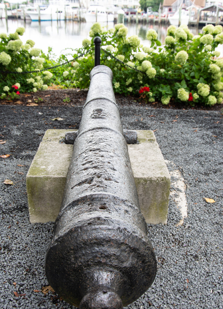 Vertical view of historic cannon at 1812 Memorial Park in Lewes Delaware with canal in background