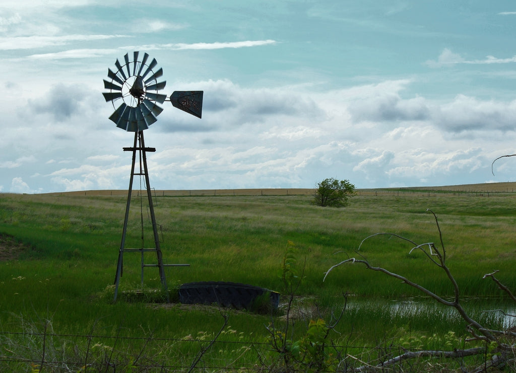 Windmill in the field with blue sky and green grass in Barber County Kansas