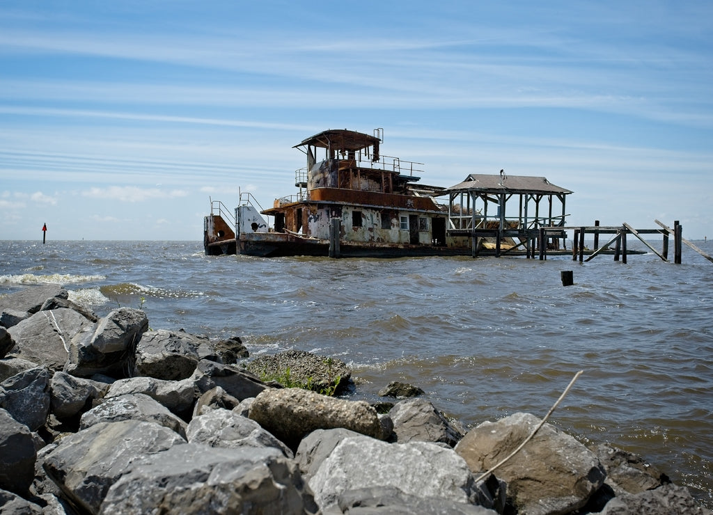 A rusted out abandon tug boat in the water just off the shore of Lake Pontchartrain in Madisonville, Louisiana