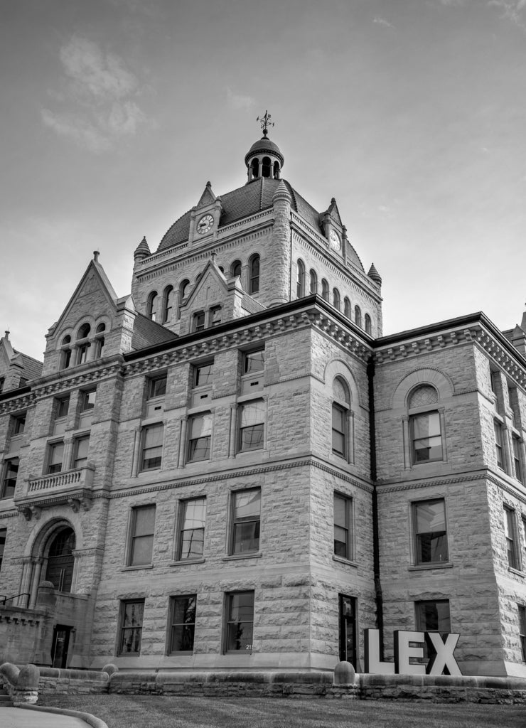 Front facade of Lexington, Kentucky history museum complex with a sign spelling abbreviation of the city in front of it in black white