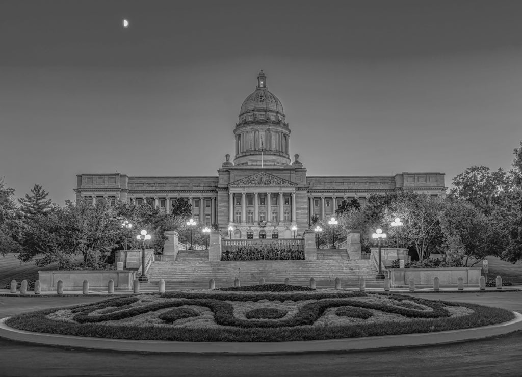 Kentucky State Capitol at dusk with warm lights illuminating this great capitol with a blue sky with a half moon on a warm summer evening in Frankfort, KY in black white