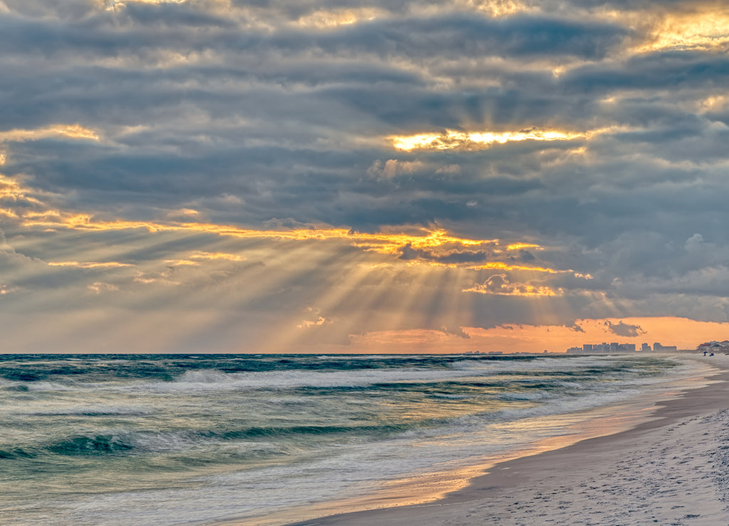 Dramatic pastel light sunset with sun rays in Santa Rosa Beach, Florida with Pensacola coastline coast cityscape skyline in panhandle and ocean