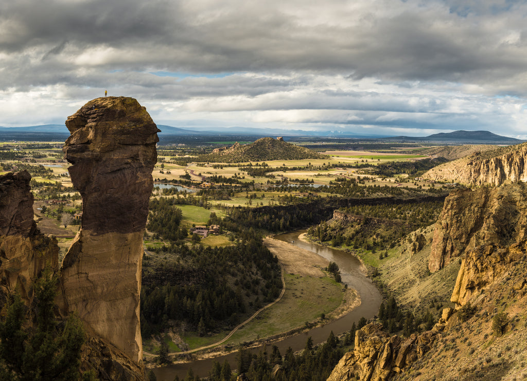 Rock climbers on top of rock spire with vast landscape in Oregon