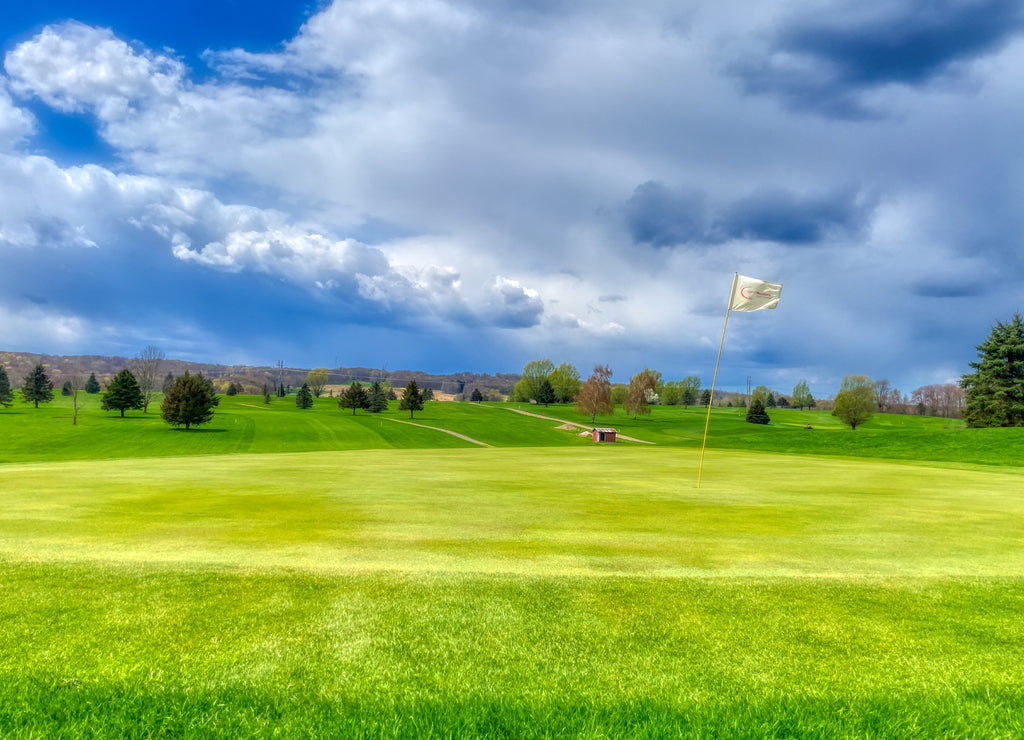 Well-kept golf course with a flagstick under a cloudy sky in Venango, Pennsylvania