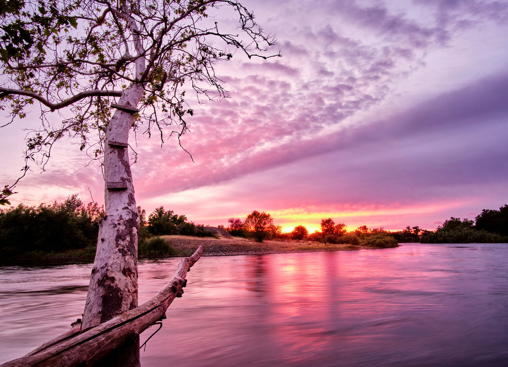 Vibrant landscape of the Feather RIver in Butte County, California with a pink and orange sunset in the background