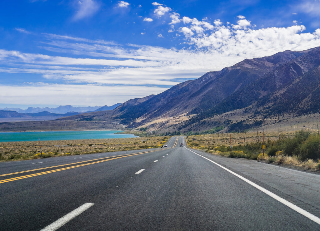 Travelling on highway 395 on a sunny day, Eastern Sierra mountains, California; Mono Lake visible on the left
