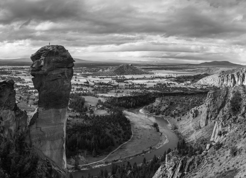 Rock climbers on top of rock spire with vast landscape in Oregon in black white