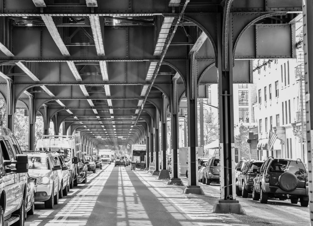 Bottom view of Elevated train track nyc. Traffic waiting in road in a sunny day. Travel and traffic concepts. Bronx, New York, USA in black white