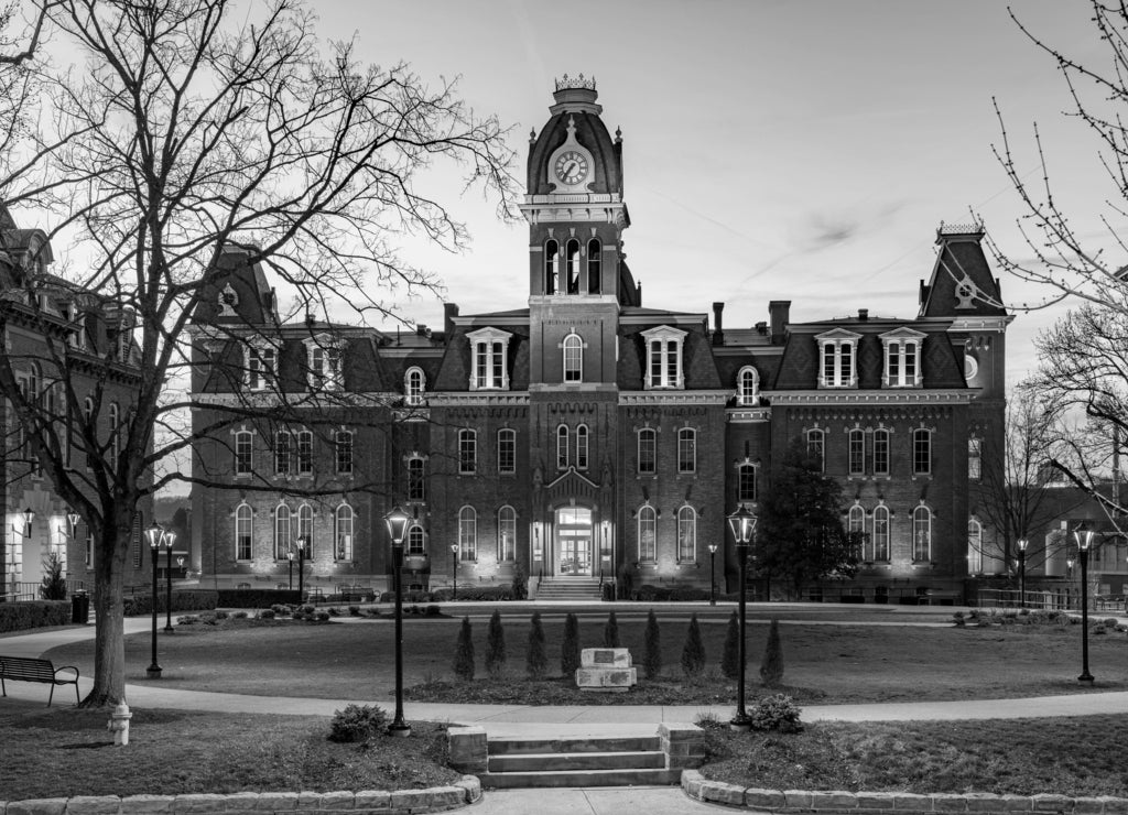 Dramatic image of Woodburn Hall at West Virginia University or WVU in Morgantown West Virginia as the sun sets behind the illuminated historic building in black white