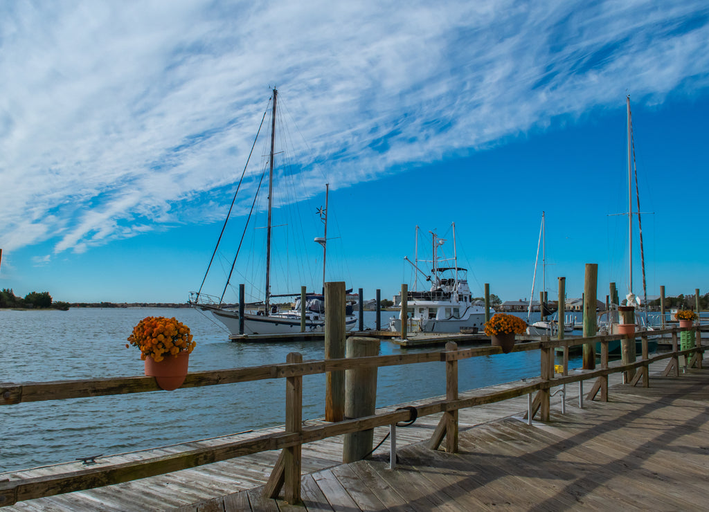 Beaufort North Carolina, Sailboats and motor boats on Taylor Creek in the harbor, blue sky above with cloud formations on a sunny day-travel inspiration